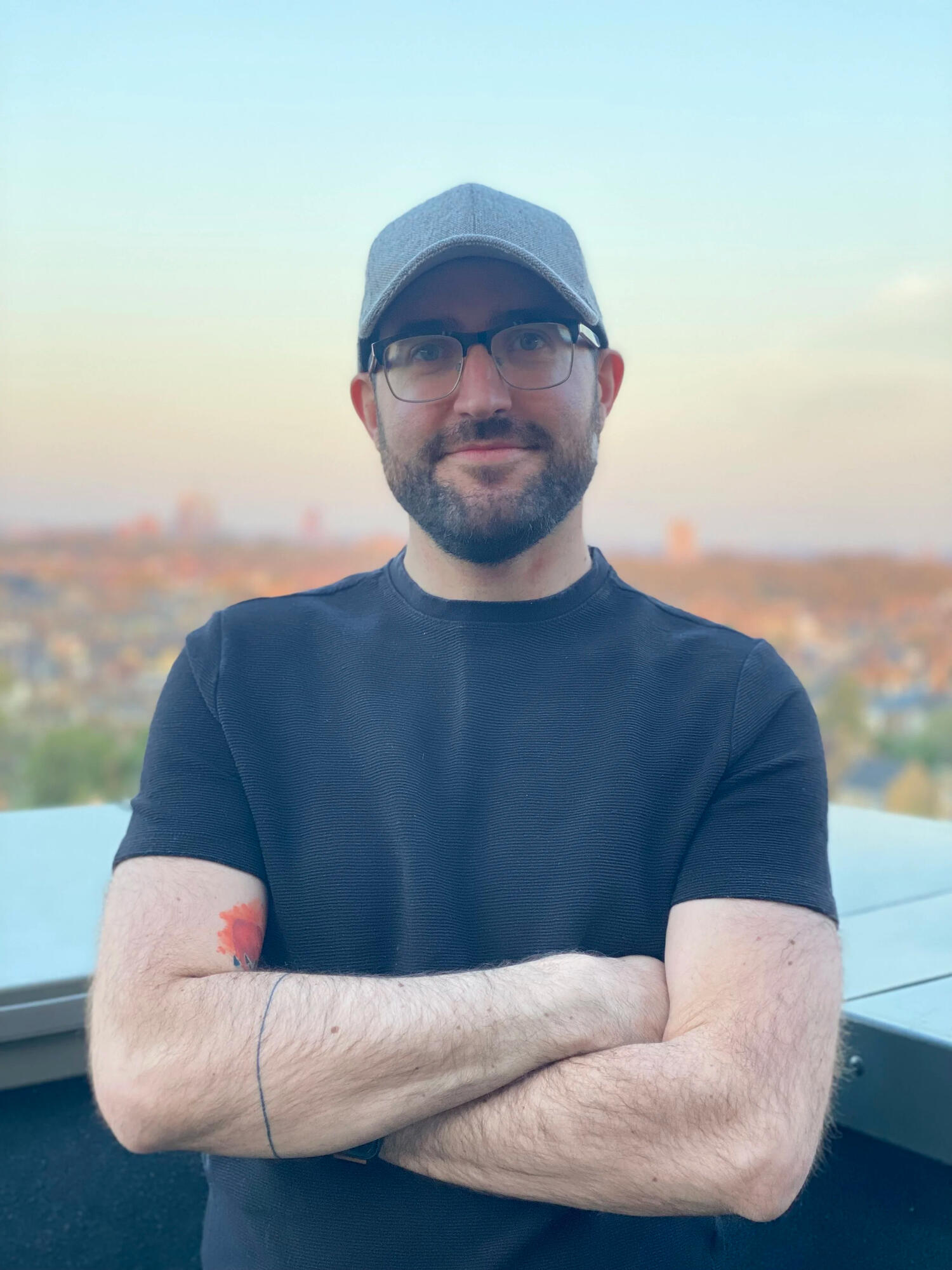Jon with arms crossed standing on a balcony